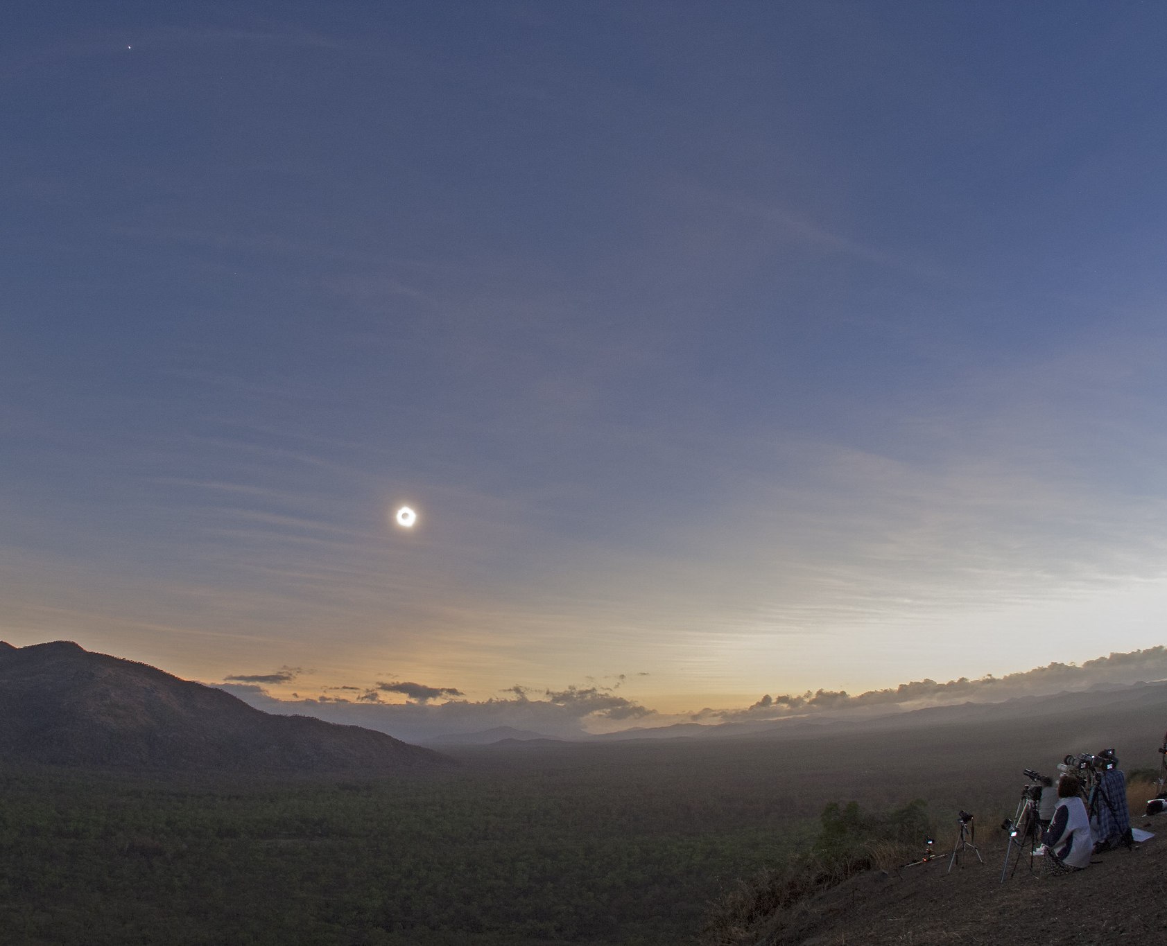Grupo de observadores fotografiando la totalidad sobre el paisaje