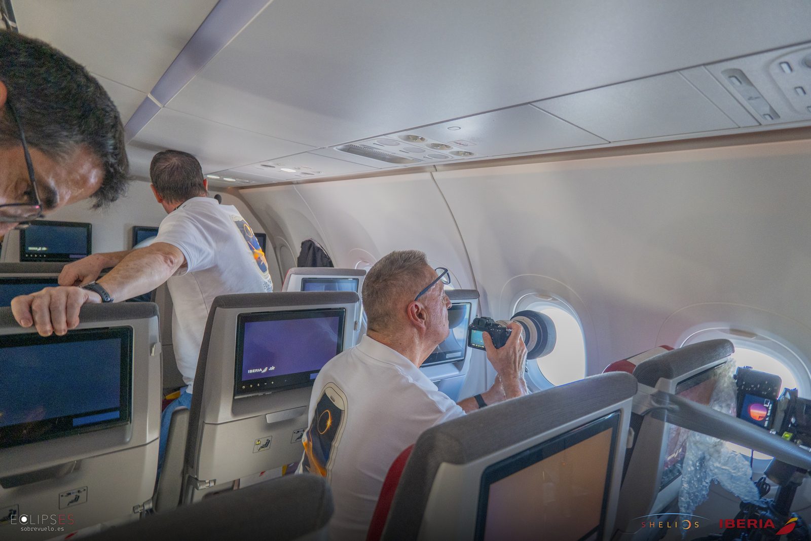 Varios miembros del equipo observan y fotografían desde sus asientos junto a las ventanillas