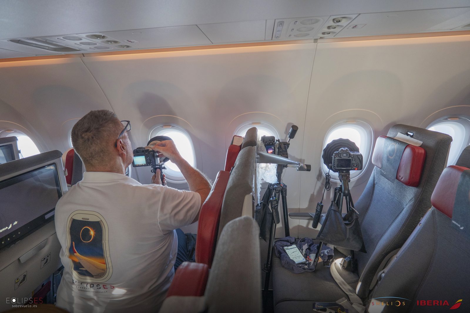 Un miembro del equipo monta cámaras sobre trípodes junto a las ventanillas del avión